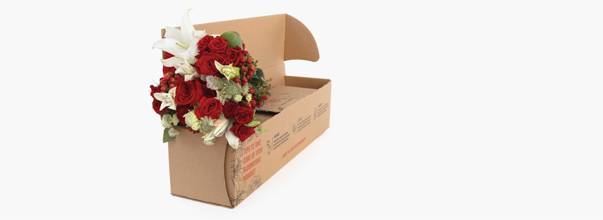 Luxurious bouquet of red roses and white lilies elegantly arranged in a delivery box.