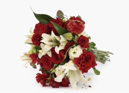 Elegant bouquet of red roses and white lilies with lush green leaves tied together, displayed against a crisp white background.