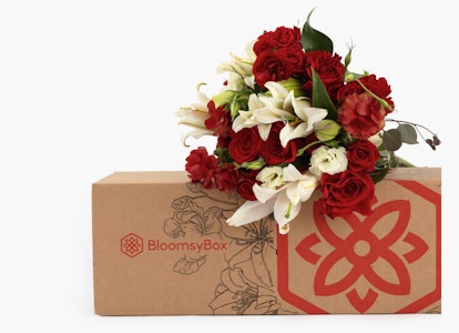 Beautiful bouquet of red roses and white lilies emerging from a BloomsyBox, against a neutral background, symbolizing a special floral delivery service.
