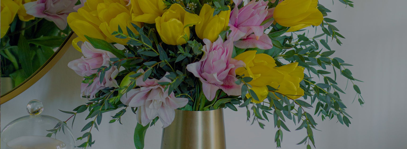 Vibrant yellow tulips and pink lilies elegantly arranged in a brass vase.