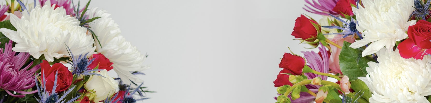 Vibrant floral arrangement featuring red roses, white chrysanthemums, and purple accents.