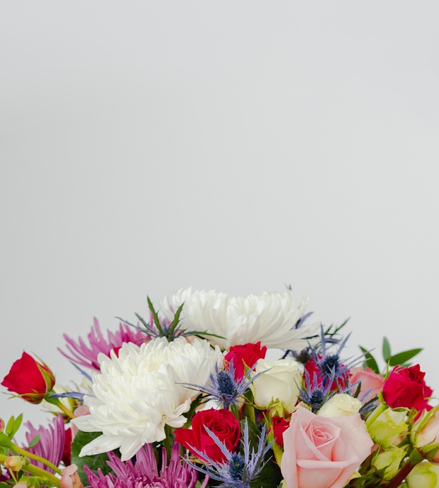 Vibrant floral arrangement featuring pink and white roses, green foliage, and colorful blooms.