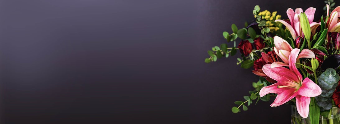 Vibrant floral arrangement featuring pink lilies and lush greenery in a stylish vase.