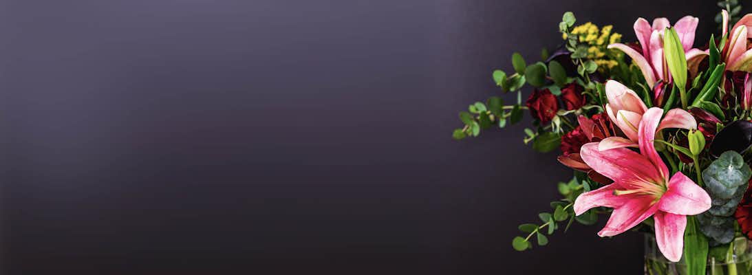 Vibrant floral arrangement featuring pink lilies and lush greenery in a stylish vase.