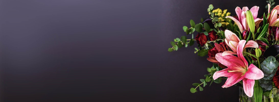 Vibrant floral arrangement featuring pink lilies and lush greenery in a stylish vase.