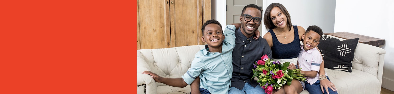 A joyful family portrait with smiles, featuring a woman holding a vibrant floral bouquet.