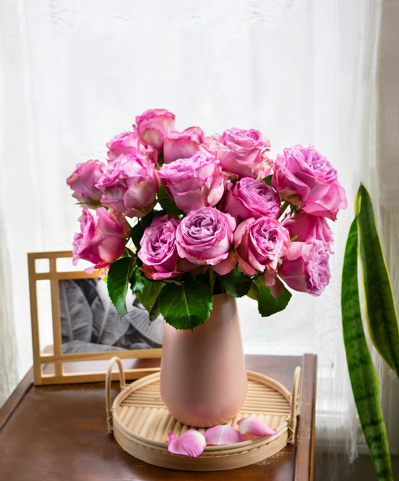 A bouquet of pink roses arranged in a soft pink vase, exuding elegance and charm.