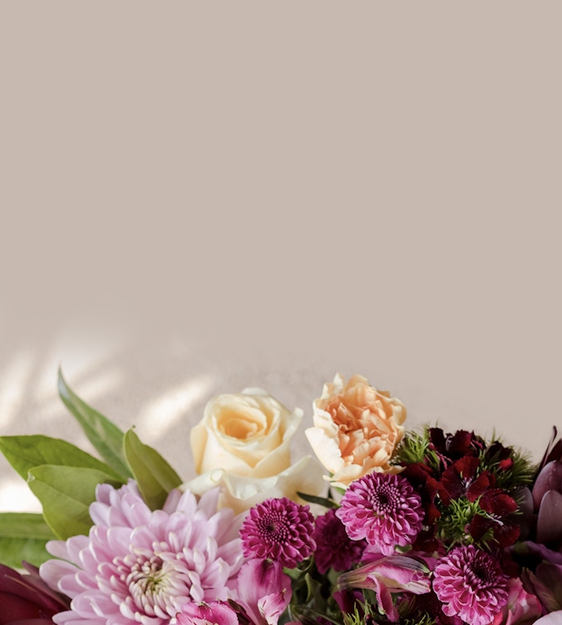 Delicate floral arrangement featuring soft pink and peach roses with lush greenery.