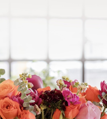 Vibrant floral bouquet featuring orange and pink roses alongside lush greenery, perfect for gifting.