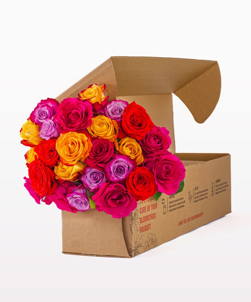 Brightly colored bouquet of roses with hues of pink, orange, and yellow, neatly packed in a cardboard flower box against a white background.