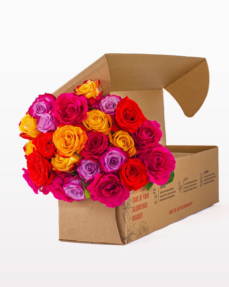 Brightly colored bouquet of roses with hues of pink, orange, and yellow, neatly packed in a cardboard flower box against a white background.