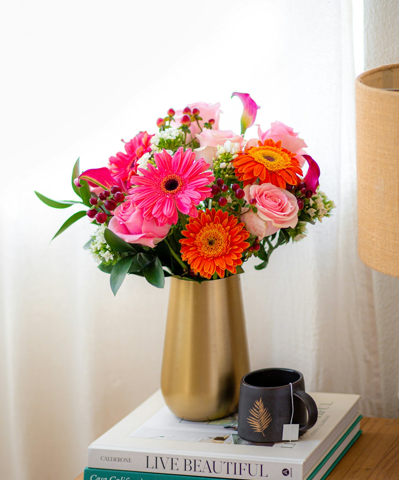 Bright and vibrant floral arrangement featuring pink gerbera daisies, roses, and orange blooms.