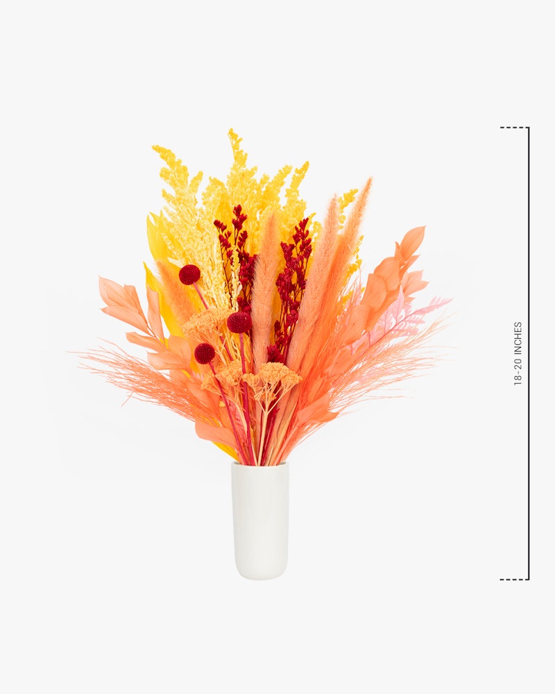 A vibrant bouquet of yellow and orange dried flowers and foliage in a white vase against a clean white background, with a ruler showing the arrangement's height.