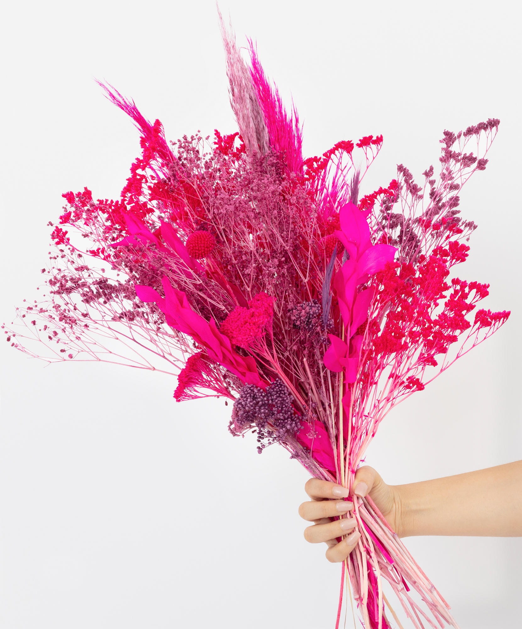 Vibrant bouquet of dried flowers in shades of pink and purple, held gracefully.