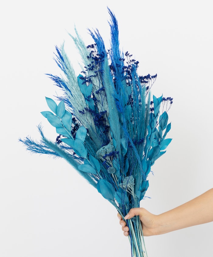 Vibrant blue floral arrangement featuring dried flowers and greenery, perfect for decoration.