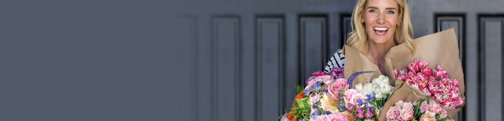 A joyful woman holding multiple flower bouquets, radiating happiness and color.