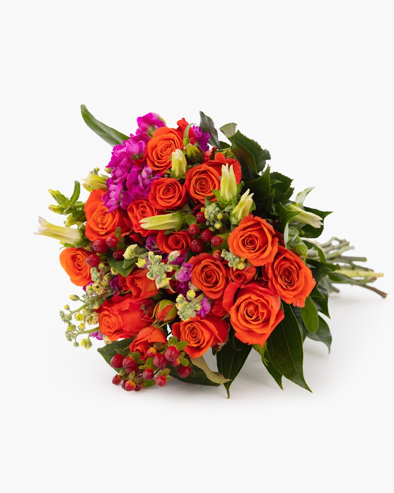 Bouquet of vibrant orange roses, purple flowers, and greenery with budding accents arranged neatly, presented against a clean white background.