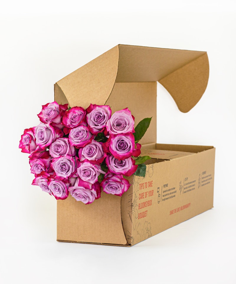 Bouquet of pink roses spilling out of an open cardboard box against a white background, symbolizing delivery of fresh flowers or a floral gift.