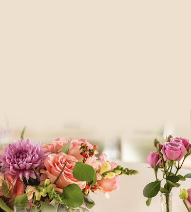 Elegant floral arrangement featuring pink roses, purple chrysanthemums, and lush greenery.