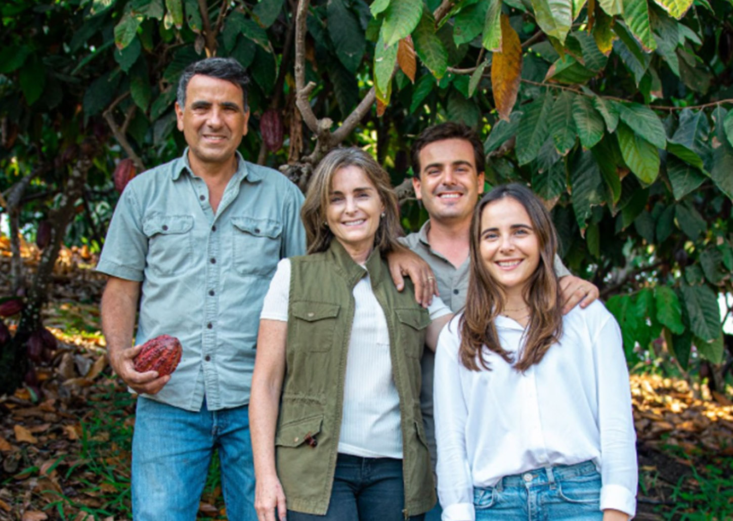 A family posing together in a cocoa plantation, surrounded by lush greenery.