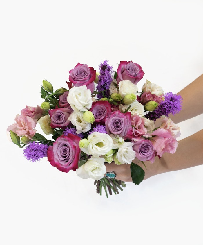 Vibrant floral bouquet featuring pink and purple roses, lush greenery, and delicate blooms.