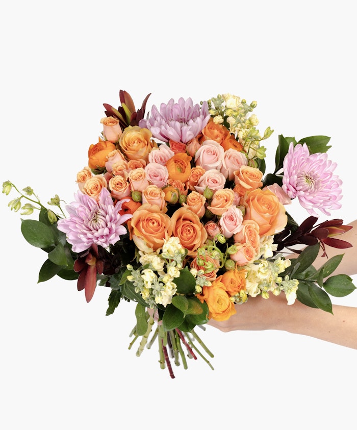 Vibrant flower bouquet featuring peach and pink roses, daisies, and greenery, ideal for gifting.