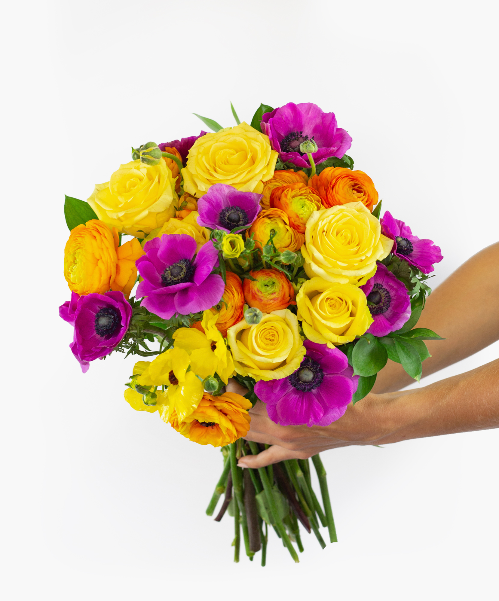 Bright and cheerful floral bouquet featuring yellow roses, purple anemones, and vibrant ranunculus.