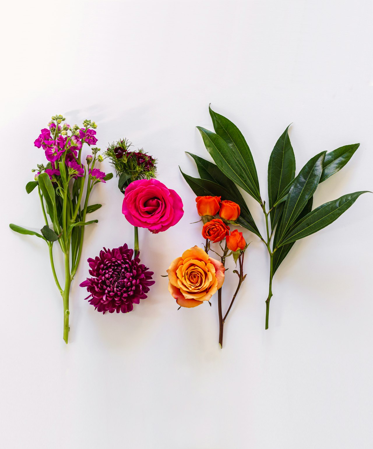 Vibrant floral arrangement featuring pink roses, orange blooms, and lush green leaves.