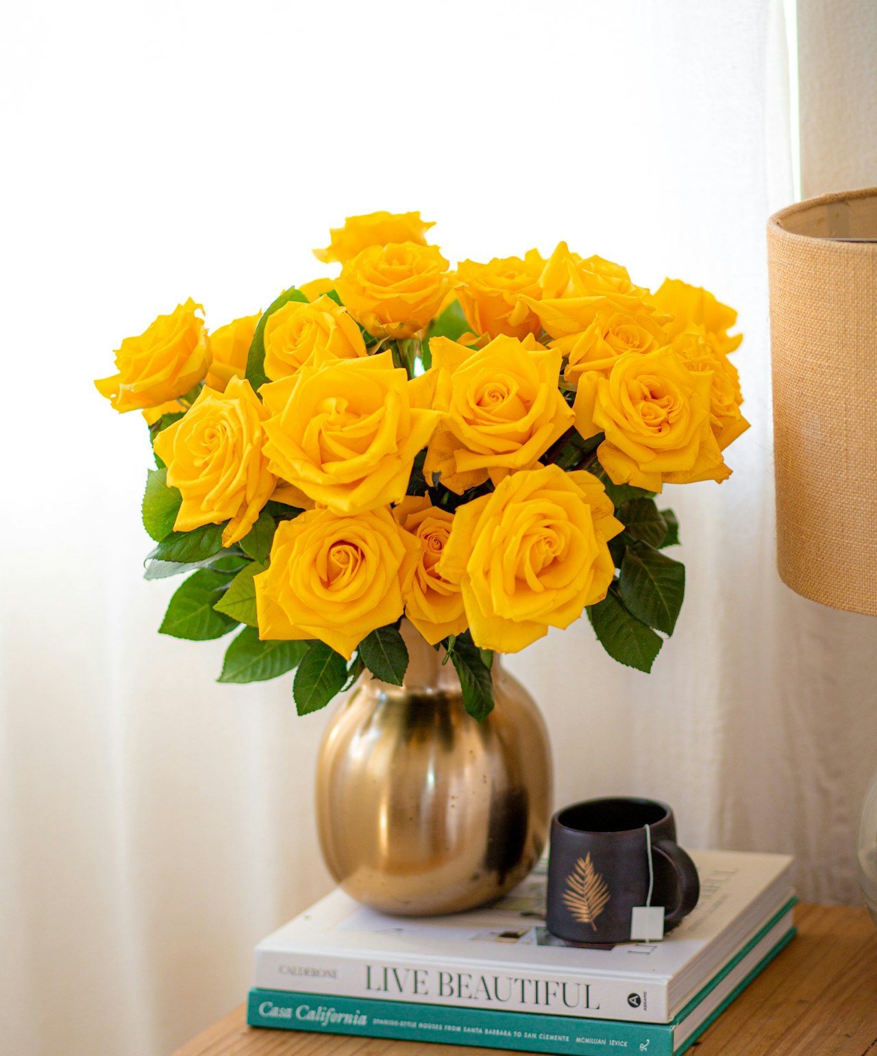 Bright yellow roses elegantly arranged in a gold vase, adding warmth to any room decor.