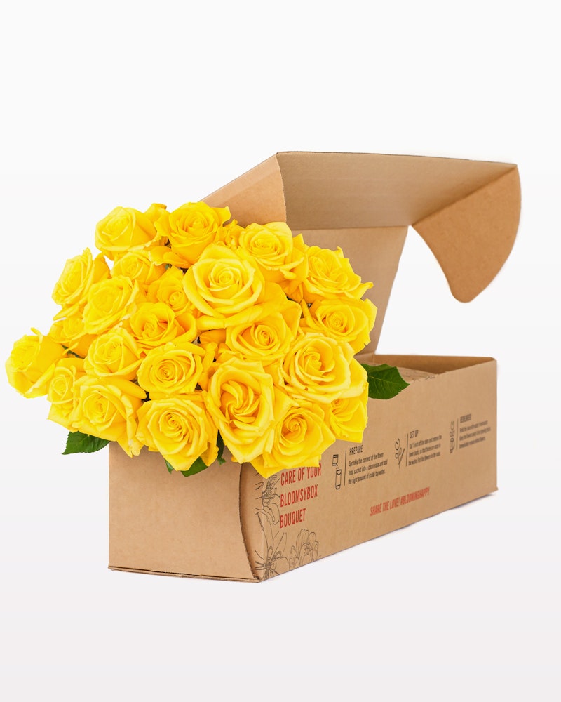 Vibrant yellow roses arranged in a cardboard delivery box on a white background, showcasing a fresh bouquet ready for gifting or decoration.