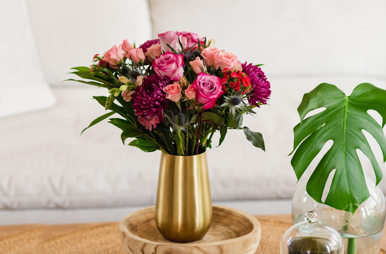 Vibrant floral arrangement featuring pink and purple roses in a stylish gold vase.