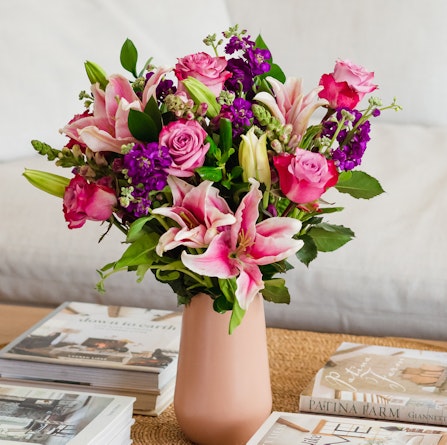 Vibrant floral arrangement featuring pink lilies, roses, and purple blooms in a chic vase.