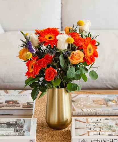 Vibrant floral arrangement featuring orange gerbera daisies and white roses in a chic vase.