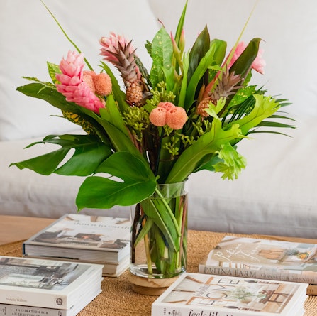 Vibrant bouquet featuring tropical flowers and lush greenery in a stylish vase, perfect for decor.