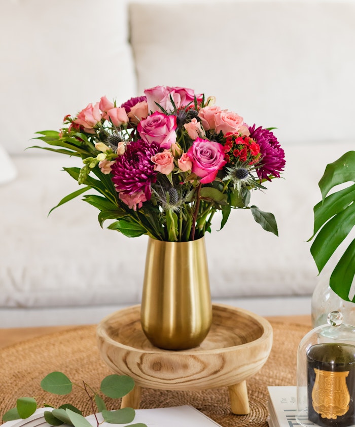 Vibrant floral arrangement of pink and purple roses in a chic gold vase, ideal for home décor.