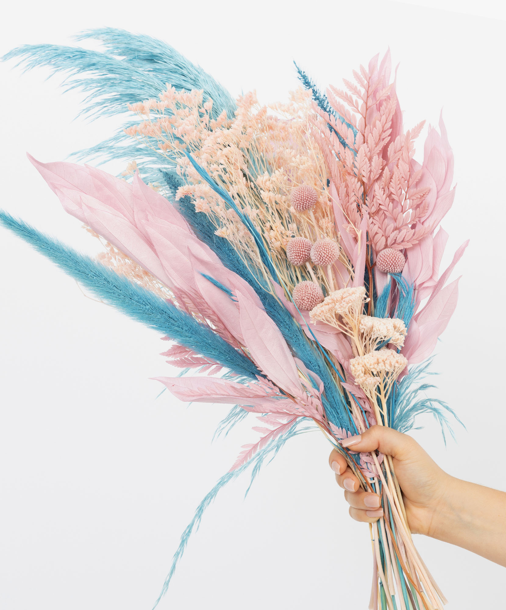 A vibrant bouquet of dried flowers in pastel pink and blue tones, held by a hand.
