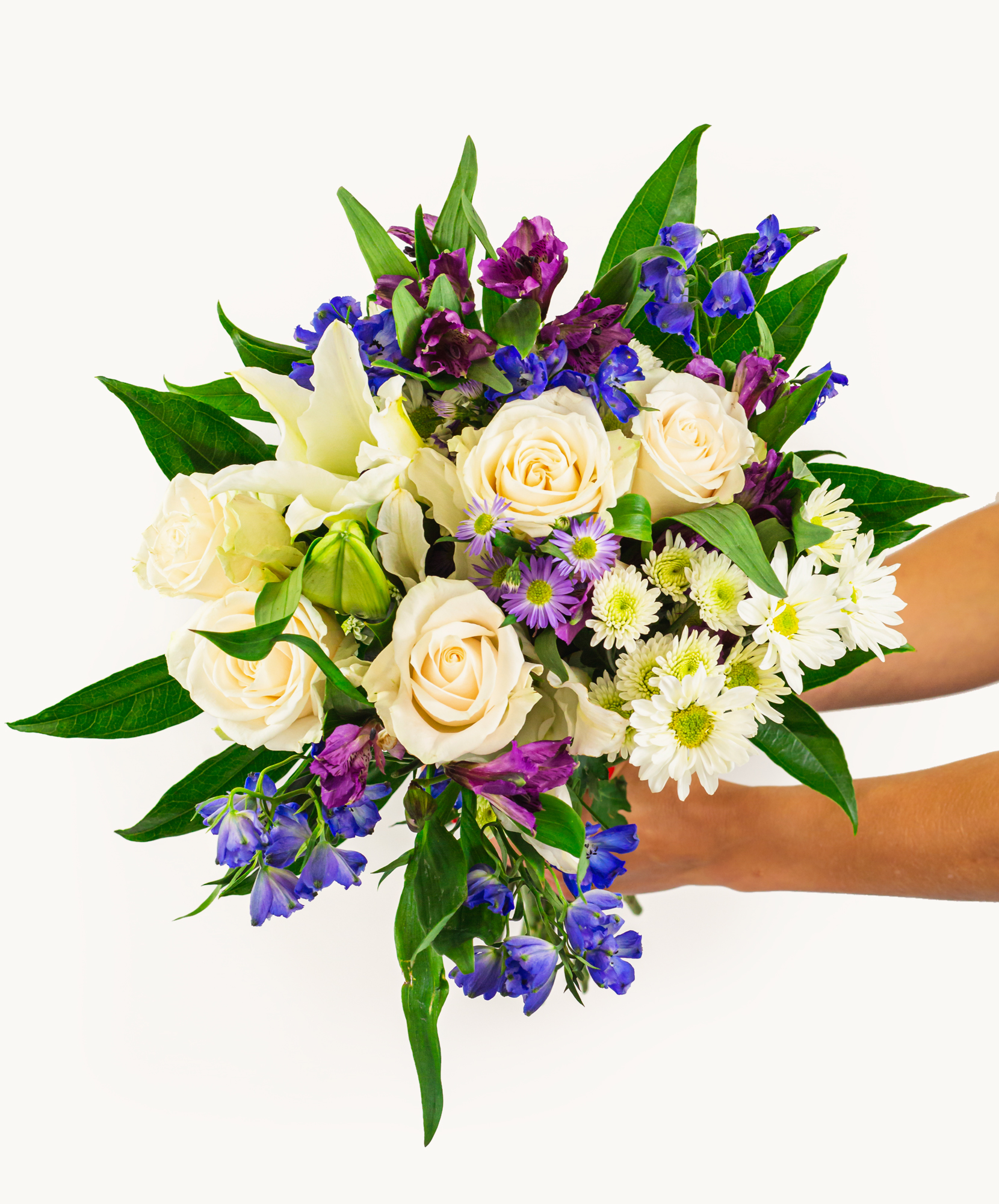 A vibrant bouquet featuring cream roses, purple blooms, and lush greens, ideal for gifts.