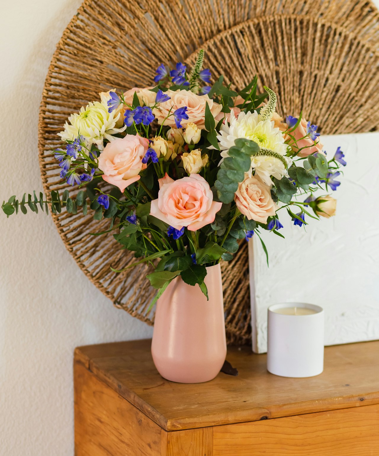 Charming floral arrangement featuring blush roses and vibrant blue blooms in a pink vase.