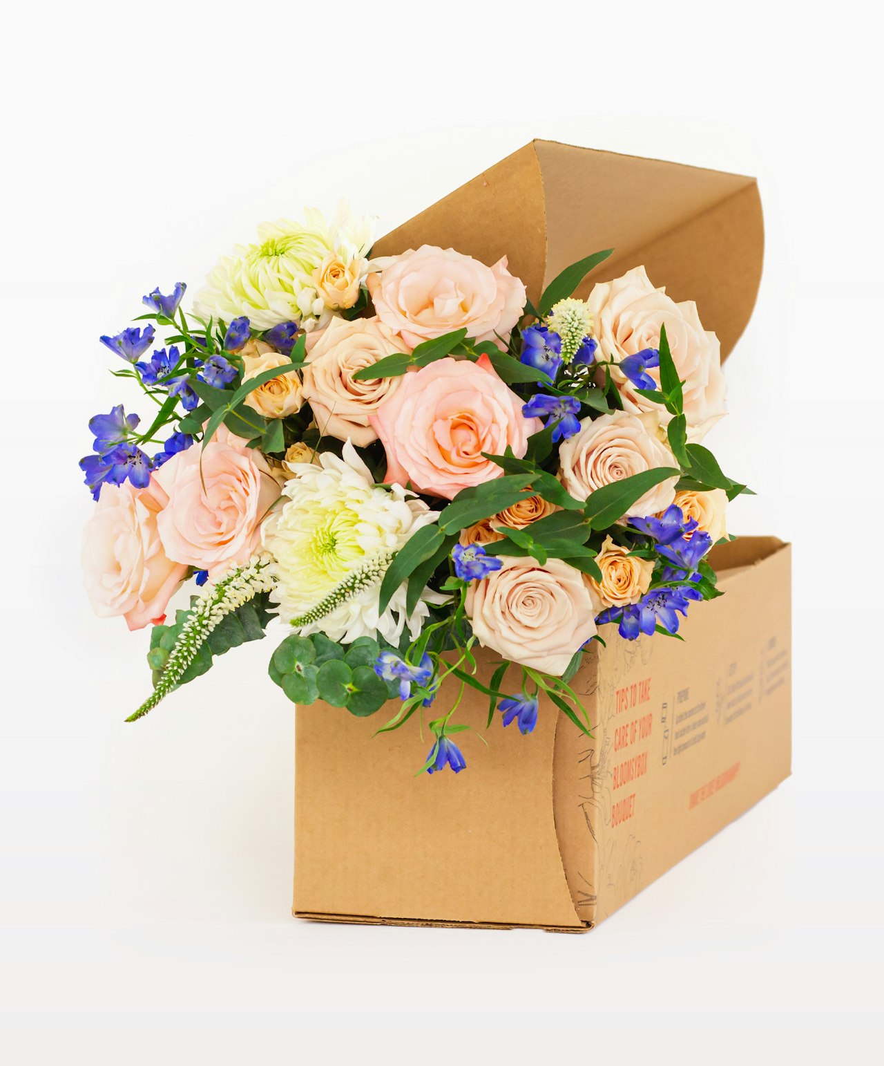 Elegant floral arrangement featuring peach roses and blue blooms in a stylish gift box.