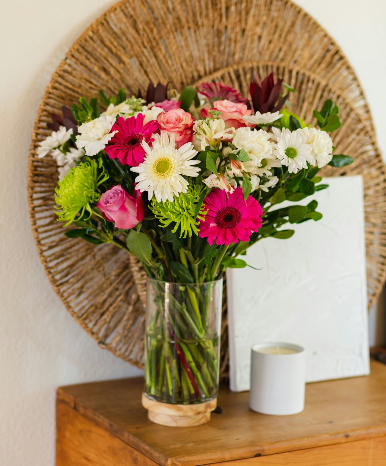 Colorful floral bouquet in a glass vase, featuring pink gerbera daisies and white roses.