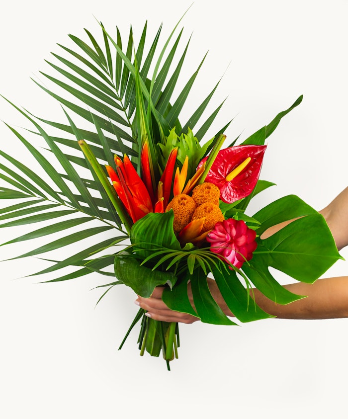 Vibrant tropical flower bouquet featuring red anthuriums, ginger, and lush greenery.
