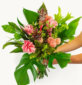 Vibrant tropical bouquet featuring pink flowers and lush green foliage, perfect for celebrations.