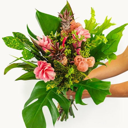 Vibrant tropical bouquet featuring pink flowers and lush green foliage, perfect for celebrations.
