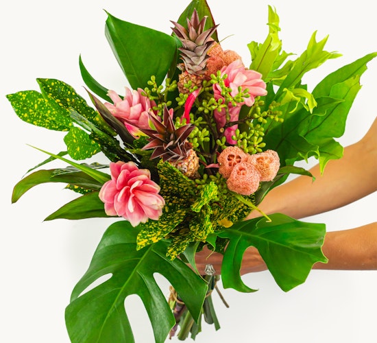 Vibrant tropical bouquet featuring pink flowers and lush green foliage, perfect for celebrations.