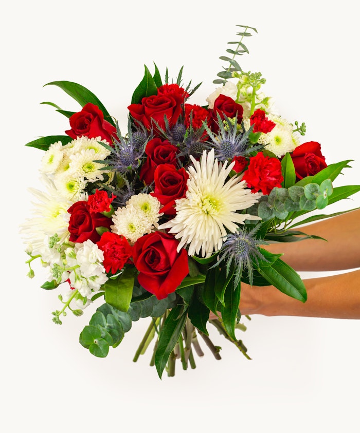Vibrant floral bouquet featuring red roses, white daisies, and greenery, ideal for celebrations.