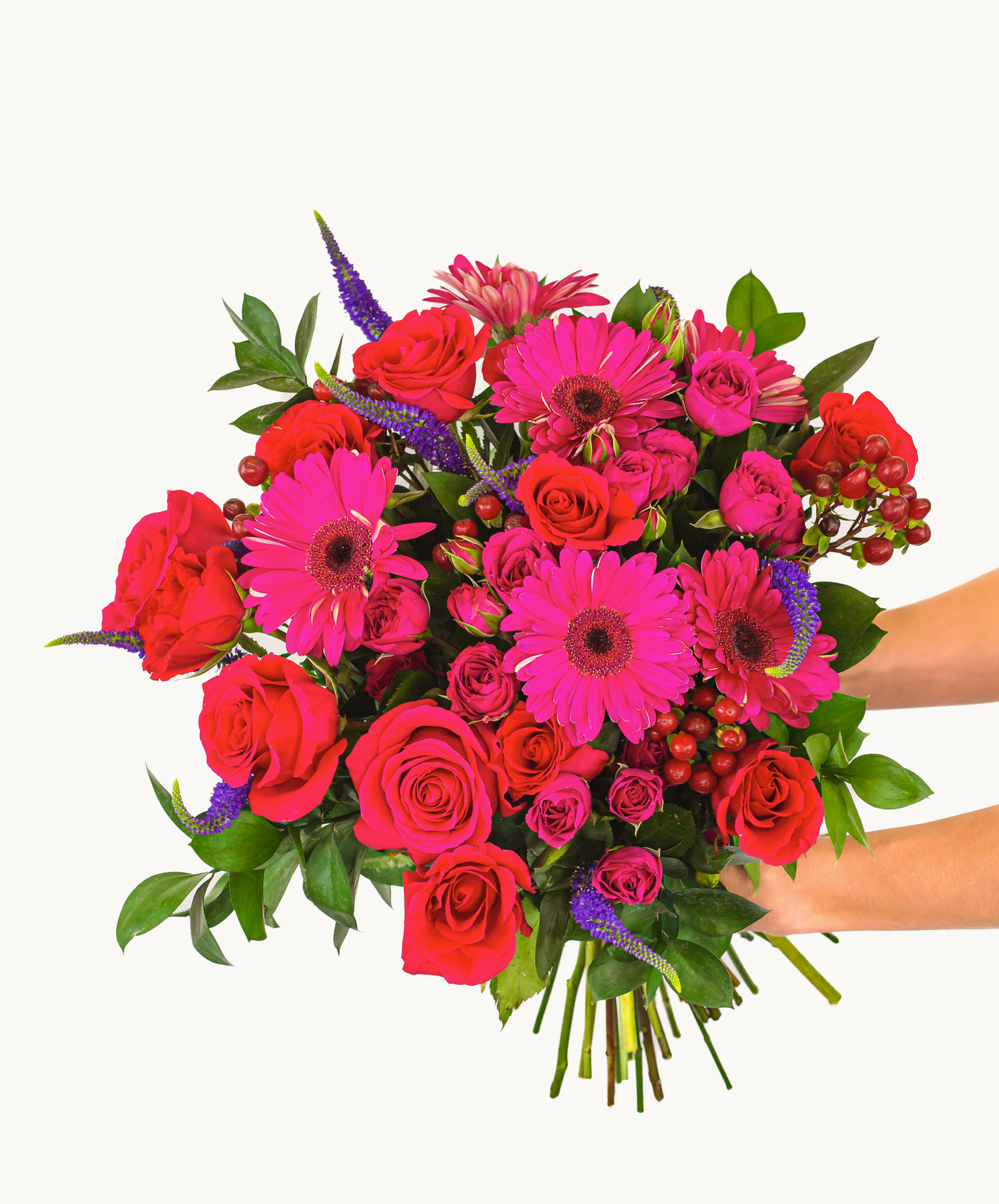 Vibrant bouquet featuring pink gerbera daisies, red roses, and lush greenery, beautifully arranged.
