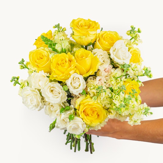 Bright yellow and white flower bouquet featuring roses and delicate blooms, beautifully arranged.