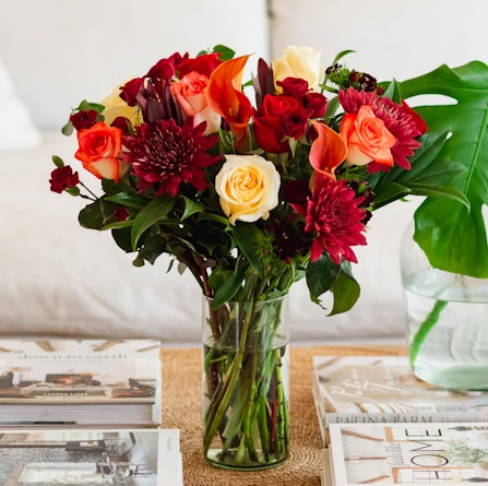Vibrant floral arrangement featuring roses, lilies, and chrysanthemums in a glass vase.