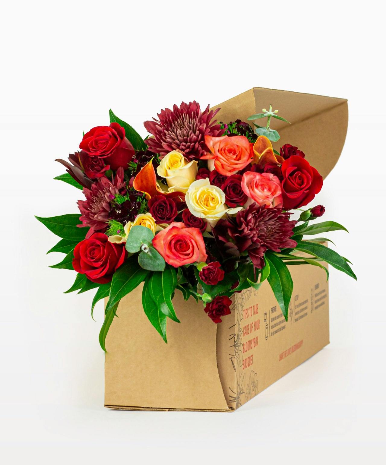 Vibrant flower bouquet featuring red roses, lilies, and greenery in a stylish package.
