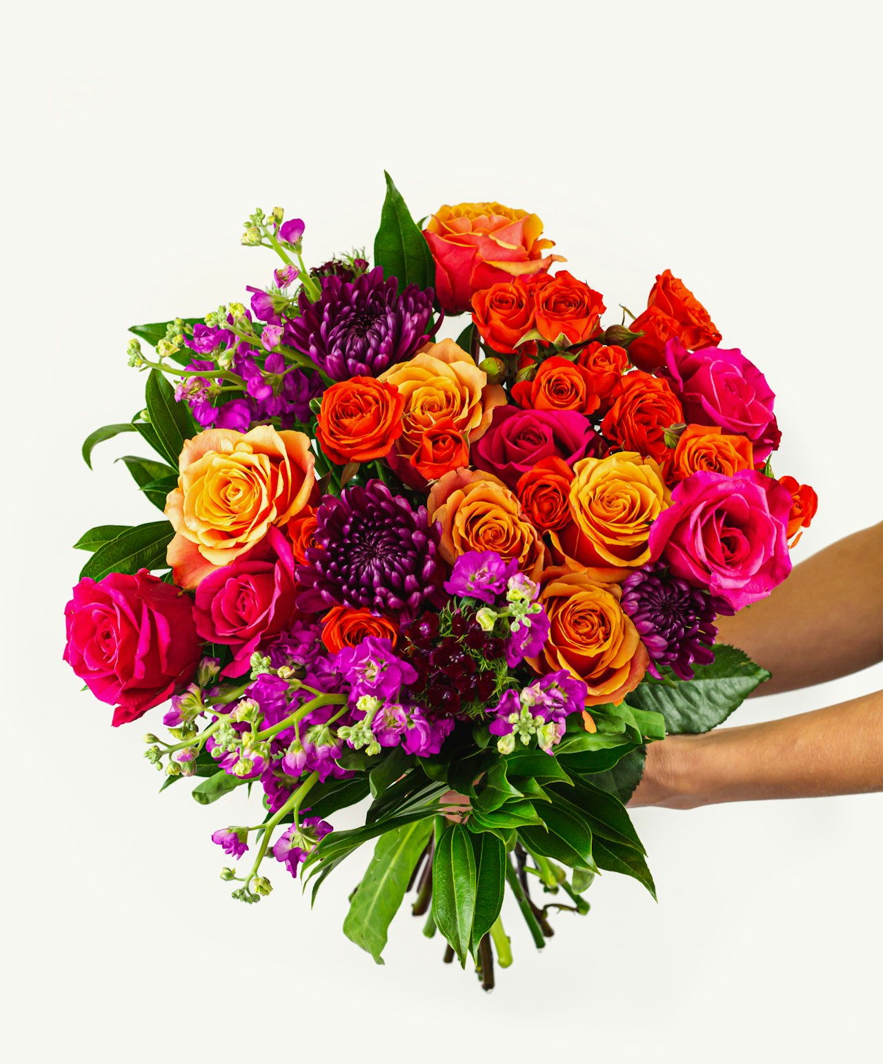 Vibrant bouquet featuring orange, pink, and purple roses with lush greenery, ideal for celebrations.
